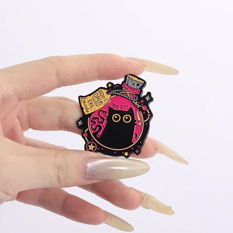 Hand holding a gothic black cat potion bottle pin, showing its compact shape and pink enamel design.