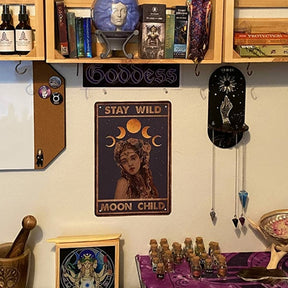 A small black celestial shelf mounted beneath a larger book shelf, with hanging pendants beside framed lunar artwork and an altar-style display.