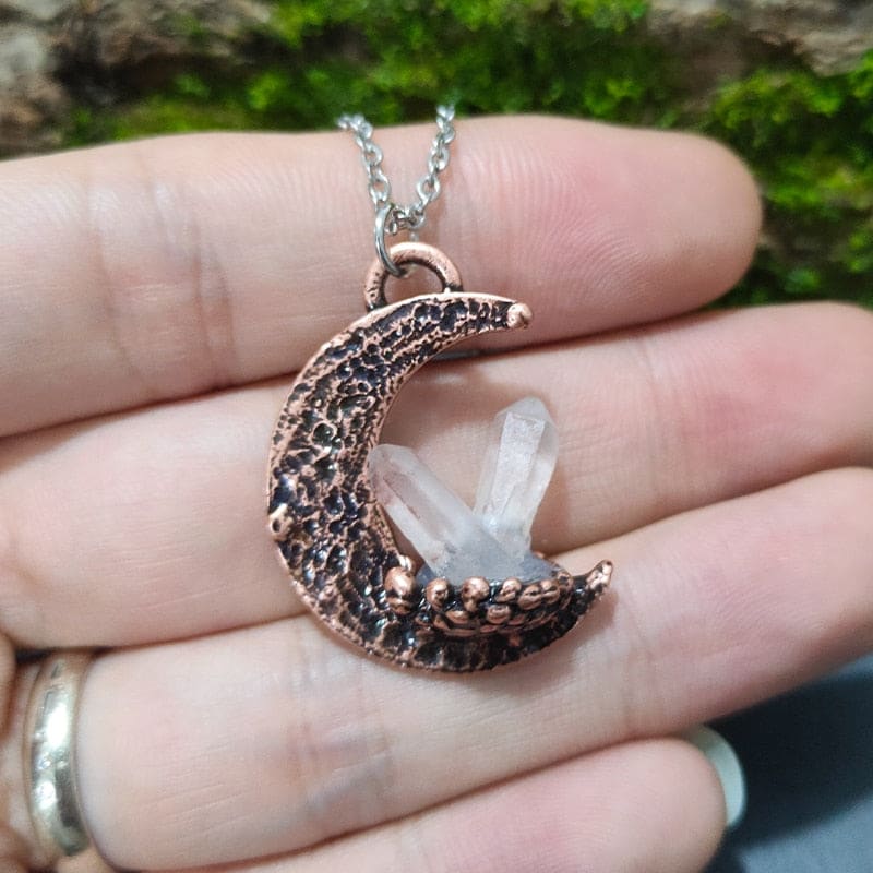 A copper-toned crescent quartz moon pendant necklace with textured finish holding clear quartz crystals