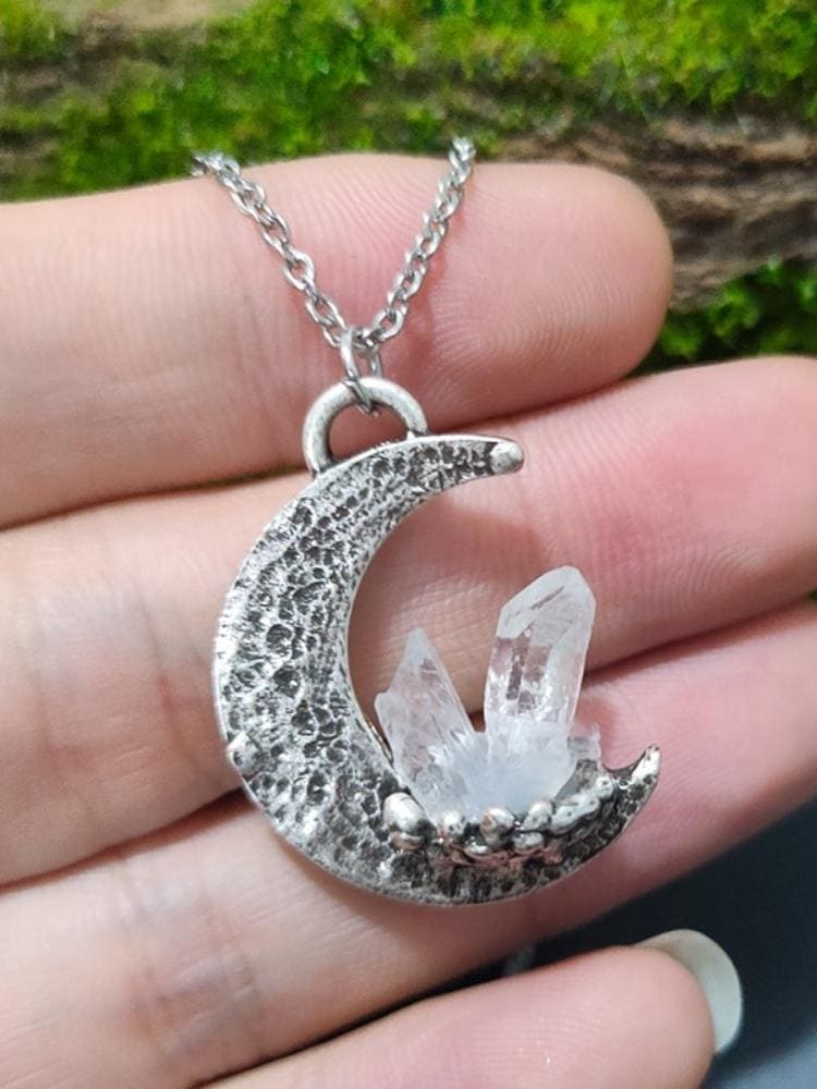 Silver crescent quartz moon pendant necklace with textured surface holding clear quartz crystals in its curve