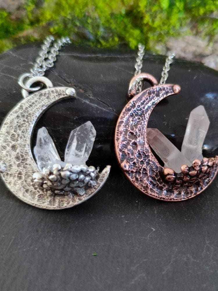 Two crescent quartz moon pendant necklaces in silver and copper tones with clear quartz crystals and hammered texture