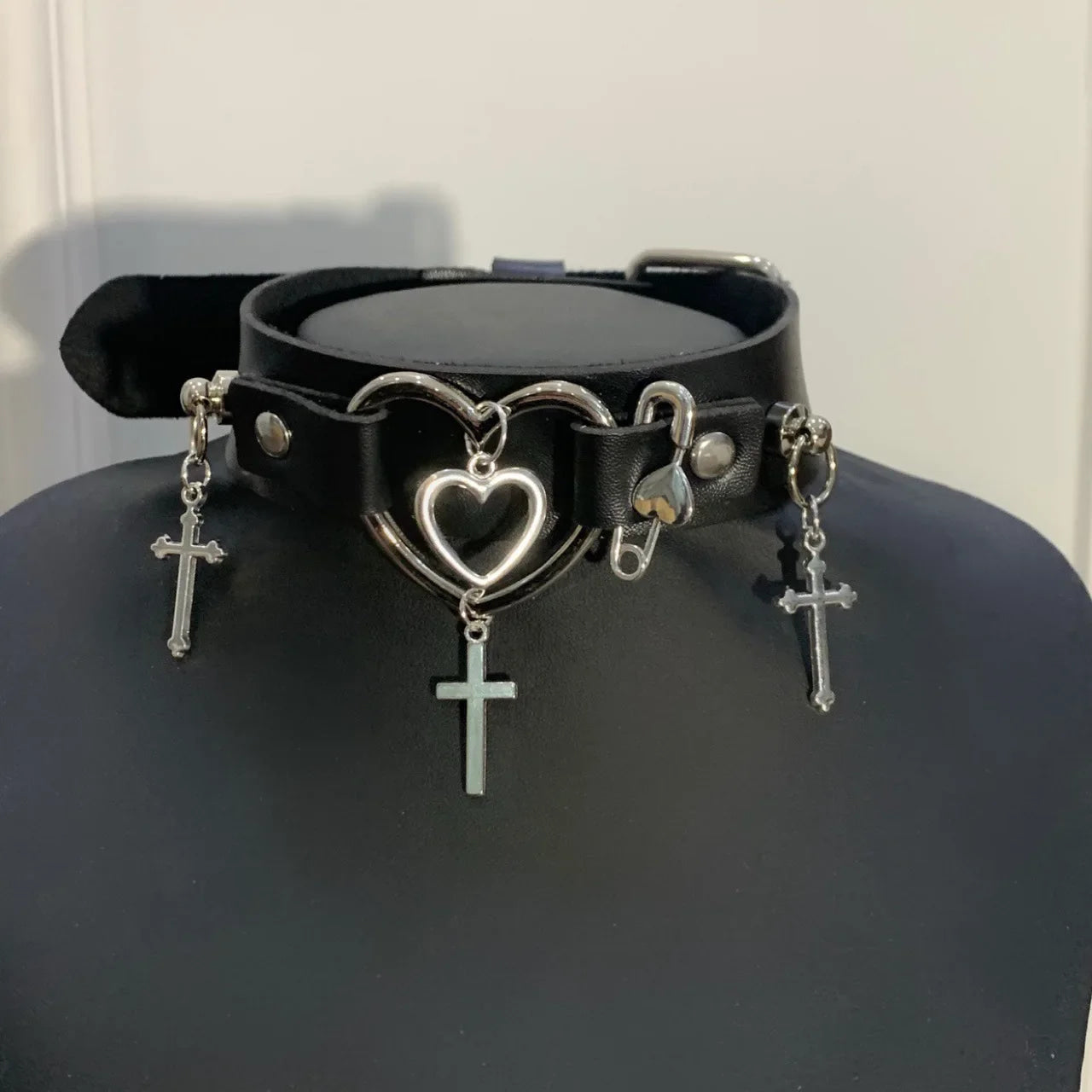 Black choker with nested open hearts, three hanging crosses and an adjustable buckle.