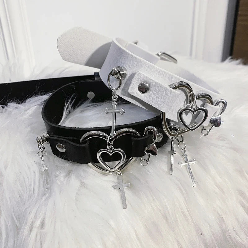 Black and white chokers with nested heart hardware, studs and dangling cross charms.