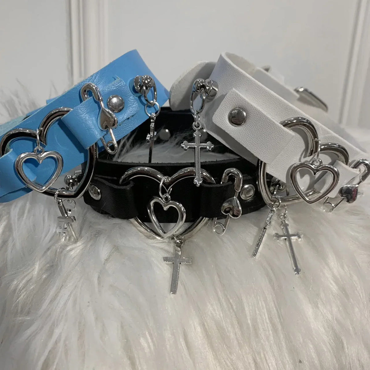 Group photo of white, black and blue display chokers showing silver-tone heart and cross details.