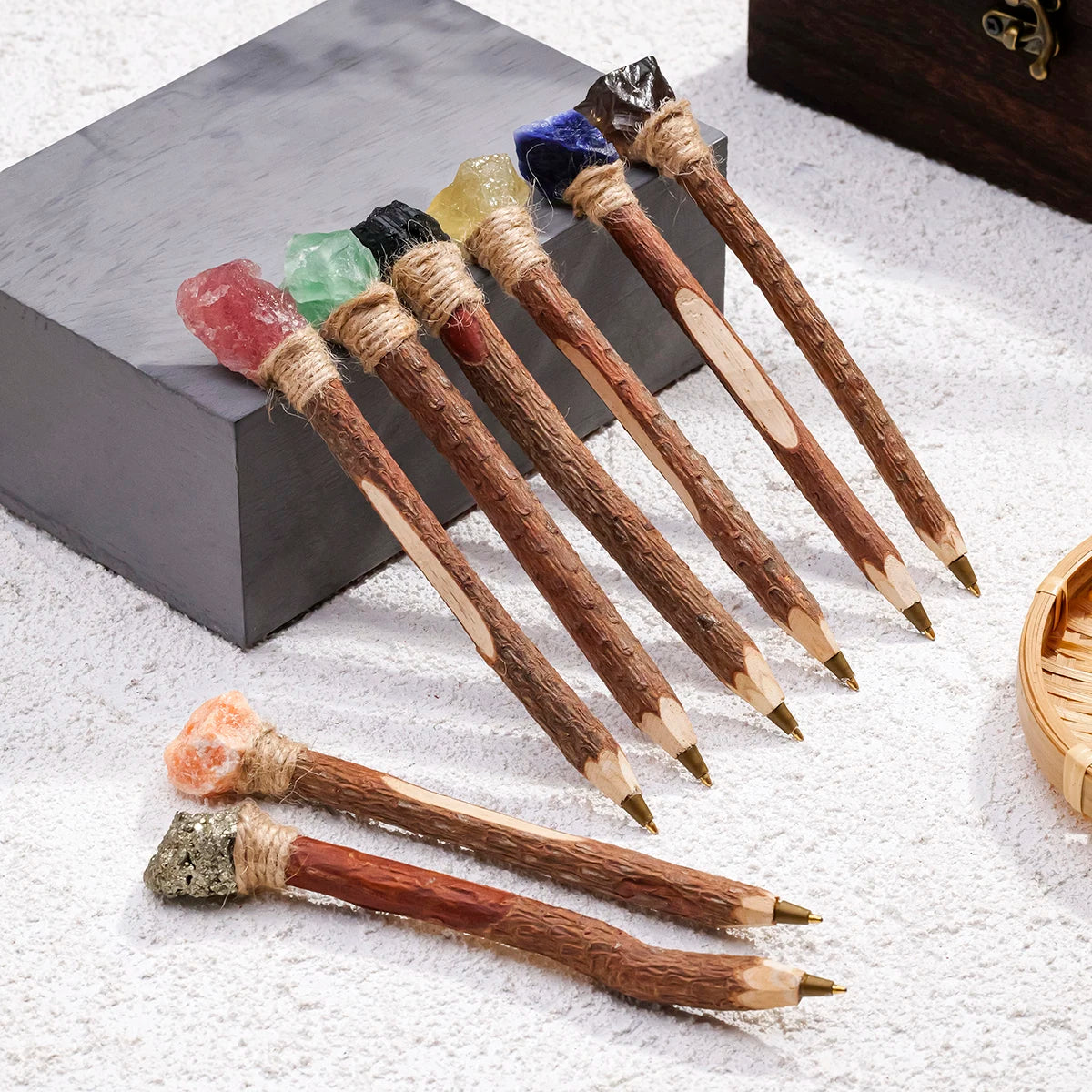 Crystal topped wand ballpoint pens with branch-like handles arranged beside a book