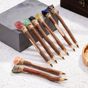 Crystal topped wand ballpoint pens with branch-like handles arranged beside a book