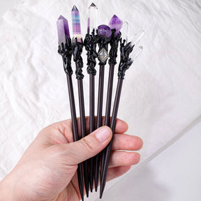 A hand holding several gothic crystal hair sticks to show their scale and toppers
