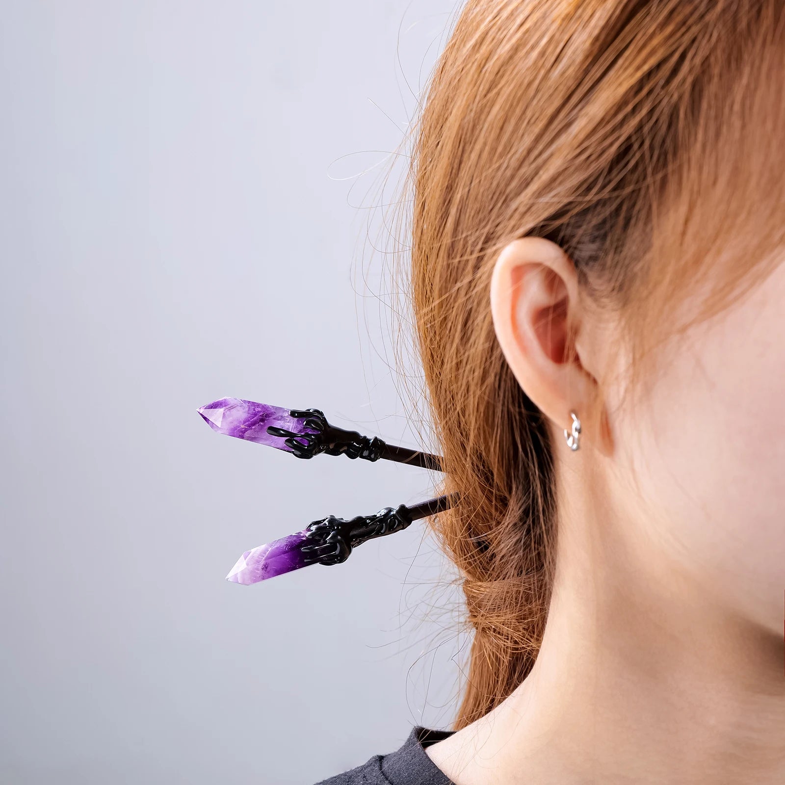 Purple crystal hair sticks worn through a twisted hairstyle