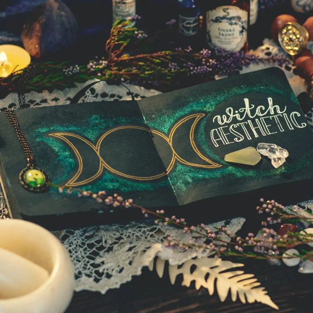 Dark green, textured notebook with gold-trimmed triple moon symbol and ’witch aesthetic’ text.