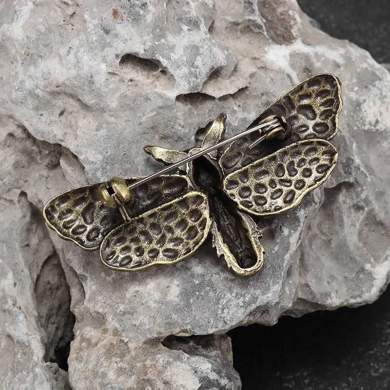 Reverse of the moth brooch on pale stone, showing the horizontal pin and fastening behind its wings.