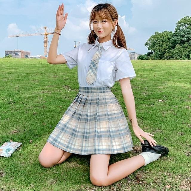 A girl wearing a beige gray plaid skirt and tie with a light blue shirt showcasing electric plaid skirt color options