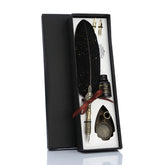 Black feather calligraphy gift set in an open box, with a red ribbon, spare nibs, bottle and ornate pen stand.