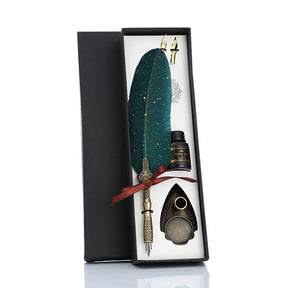 Green feather quill gift set arranged in an open black box with an ornate stand, spare nibs and bottle.