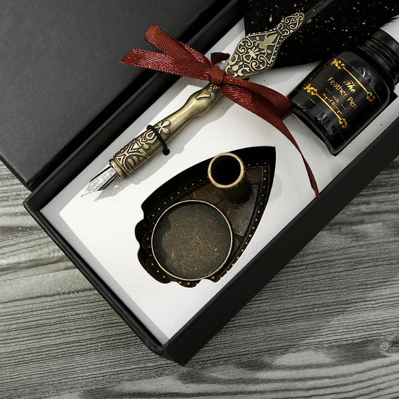 Close view of a feather quill gift box showing the decorated handle, red ribbon, empty bottle and shield-shaped pen stand.