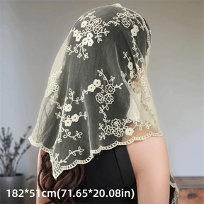 Beige lace hair scarf draped over dark hair, showing its floral pattern and scalloped border with dimensions below.