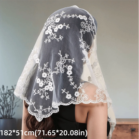 White floral lace triangle headscarf over dark hair, with scalloped borders and printed dimensions.