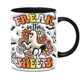 Additional view of the black-handled Freak in the Sheets mug, showing a central white ghost, flowers and bold curved lettering.