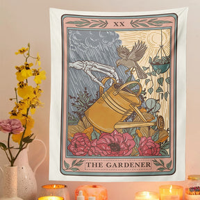 The Gardener tapestry displayed above candles beside yellow flowers, with a watering can and red blooms in the print.