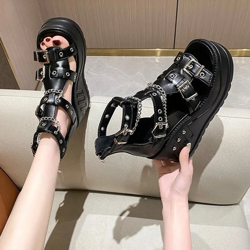 Hand-held black wedge sandal showing chain and buckle construction