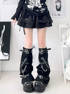 Black flared leg warmers worn with a short skirt, showing upper buckle straps and chains along the fronts.