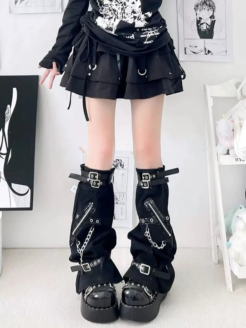 Black flared leg warmers worn with a short skirt, showing upper buckle straps and chains along the fronts.
