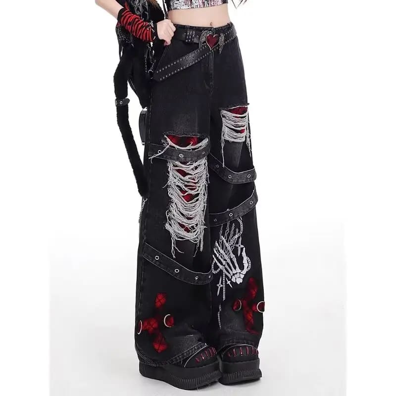 Close-up of black ripped wide-leg jeans with red crosses, skeletal hand artwork, eyelet straps and frayed threads.