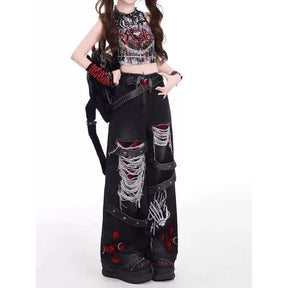 Model wearing black wide-leg gothic jeans with heavy fraying and red cross details, styled with a cropped top.