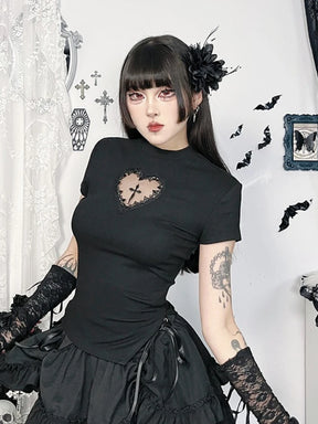 Black heart-cutout cross T-shirt styled with lace arm warmers and a ruffled skirt, photographed in a seated pose.
