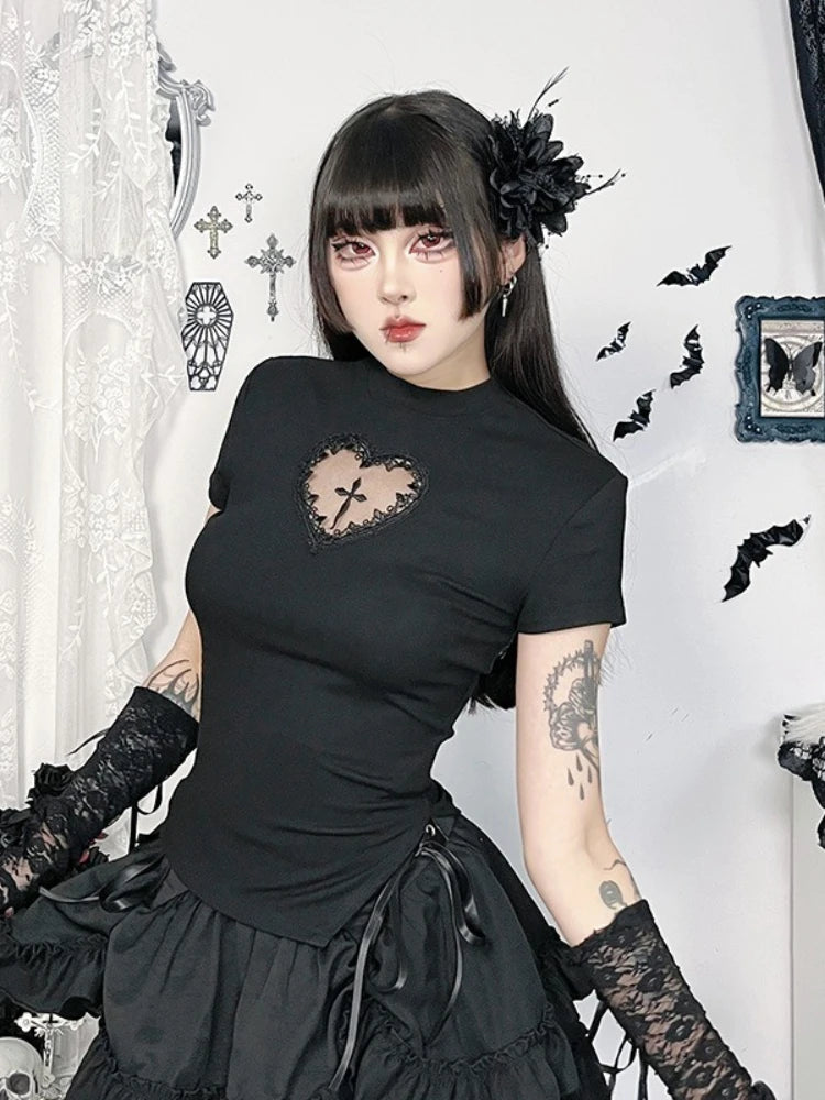 Black heart-cutout cross T-shirt styled with lace arm warmers and a ruffled skirt, photographed in a seated pose.