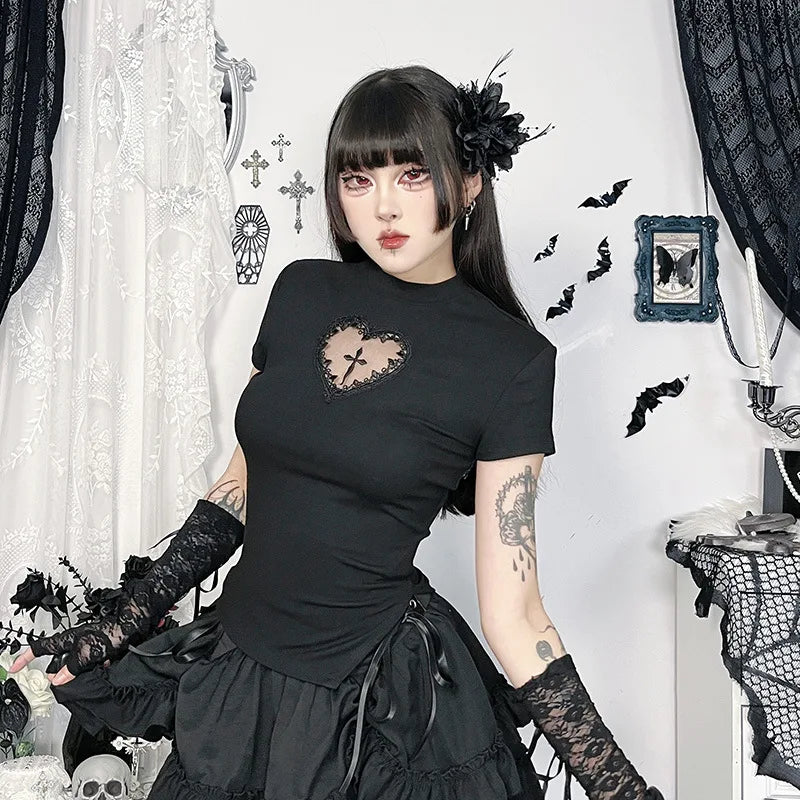 Black gothic T-shirt with a lace-edged heart cutout and central cross, worn with a ruffled black skirt. A seated pose against white lace curtains shows the short sleeves and shaped hem.