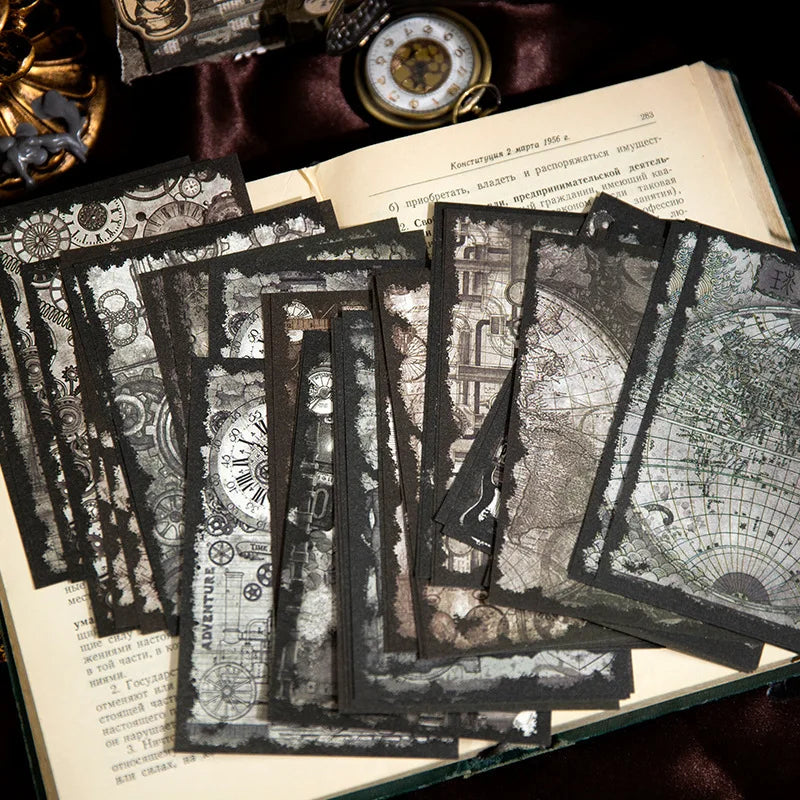 Monochrome gothic journaling paper fanned over an open book, with maps, clocks and dark illustrated borders.