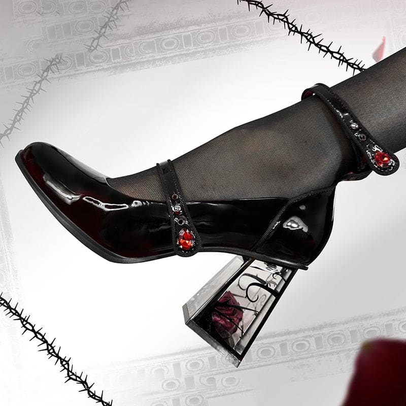 Full side profile of a glossy wine-red Mary Jane against a decorative frame, with red jewel accents, rounded toe and transparent rose-filled block heel.