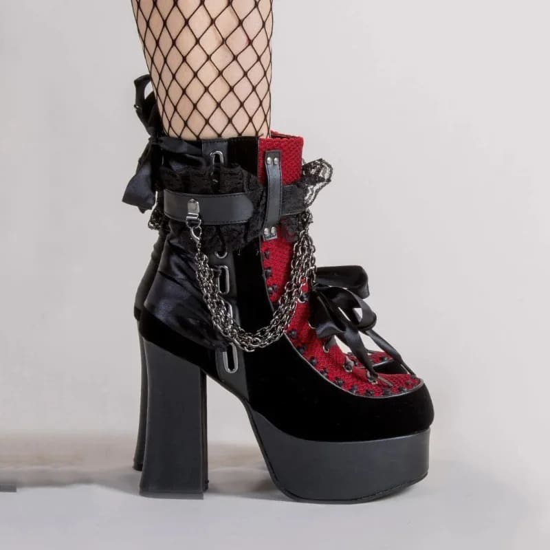 Side view of a red gothic ankle boot on a model, showing its thick platform, block heel and black bow.