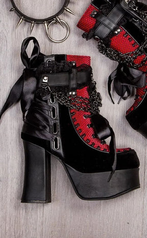 Red lace platform boots arranged on a wooden floor with a separate styling accessory beside them.