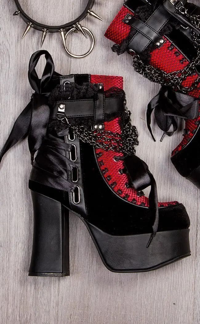 Red lace platform boots arranged on a wooden floor with a separate styling accessory beside them.