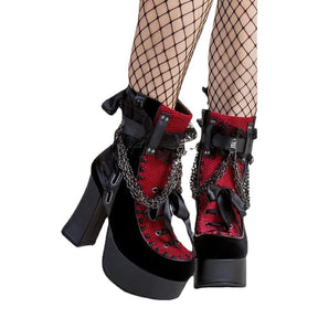Red lace and bow platform boots worn with fishnet tights, showing chunky heels and ribbon front lacing.