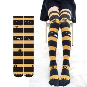 Black and yellow striped Halloween thigh high stockings with creepy cute witch silhouettes pumpkins ghosts and haunted houses