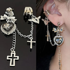 Two-panel view of a faceted heart chain earring against black and the same style worn on an ear. The bow, upper-ear cuff and long cross drops are visible together.