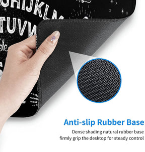 A corner of the Ouija mousepad lifted to show its textured black rubber backing and stitched border, with a magnified inset of the underside pattern.