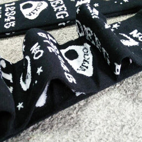 Detail of the black stocking fabric gathered into soft folds, showing white moons, stars and planchette motifs.