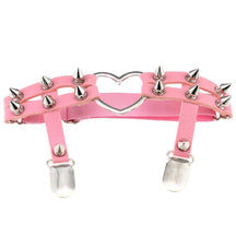 Pastel pink thigh garter with two spiked front bands surrounding a silver-tone heart ring and two stocking clips below.