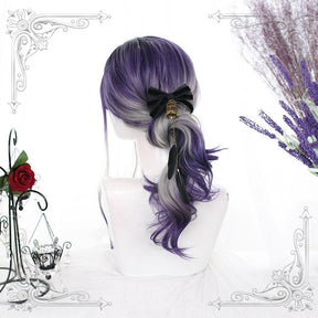 Side view of the purple and gray wig gathered behind a black bow, with curled violet ends falling beside a white mannequin neck.