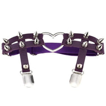 Purple thigh garter shown on white with silver-tone cone spikes across the twin front straps, a heart ring and two stocking clips.