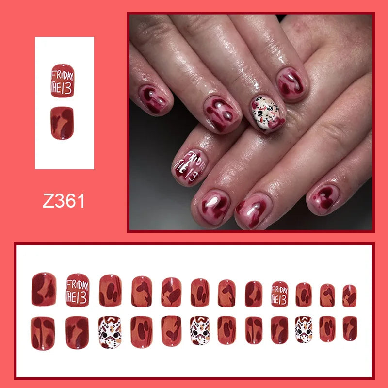 Red rounded false nails with dark horror graphics and a pale mask design, shown worn with a row of matching nail tips.