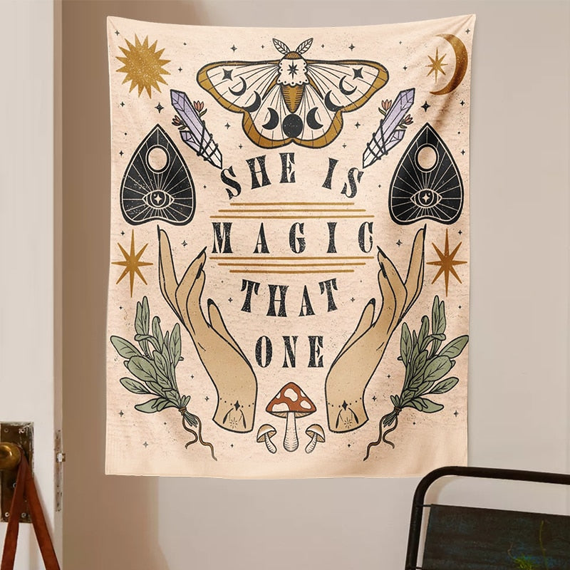 Beige witchy tapestry displayed on a light wall above a chair, with moth wings and moon phases above the printed words.