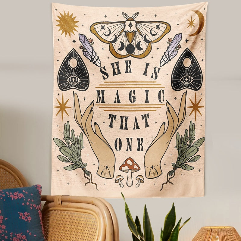 Witchy beige tapestry above a woven chair and green plants, showing its dark lettering and muted botanical artwork.