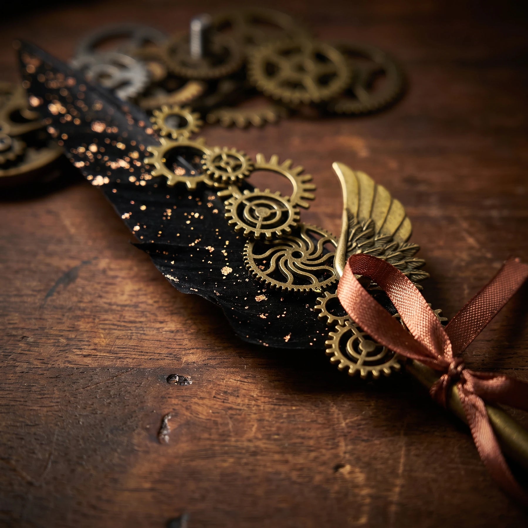 Close-up of gold-tone gears and a wing ornament on the black steampunk quill