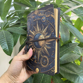 Angled view of the sun-and-moon journal showing its page edges and gold-coloured artwork on a dark cover.