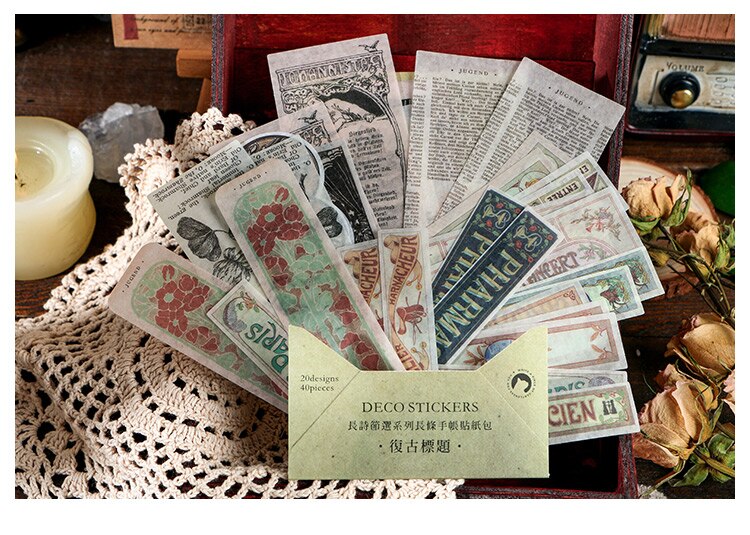 Old advertising and label-style stickers fanned from a muted green packet on a vintage-inspired craft surface.