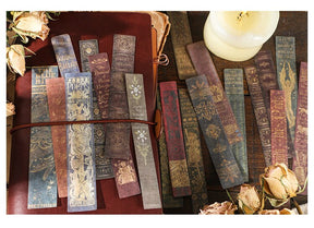 Long vintage book-spine stickers in muted red, brown and green arranged over a journal, with ornate printed lettering.